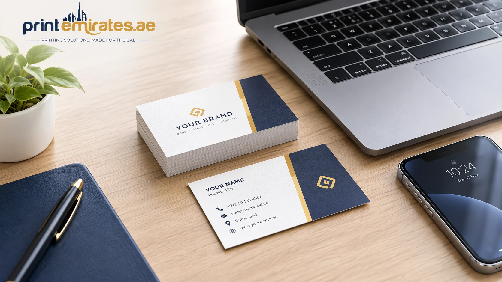 Set of printed business cards laid on a desk beside a laptop and a phone 